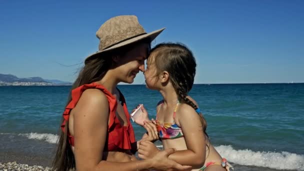 Small girl hugging her mom on the beach. They smiling. Summer sunny day. Happy Mothers day. — Stock Video