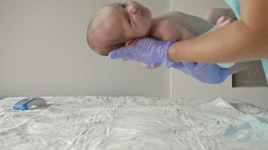 Pediyatrist, yeni doğan bebeği muayene masasına koyar..