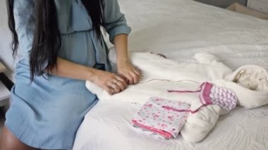 Sevimli hamile kadın, doğmamış bebek için hazırlanmış şeylere hayran kalır..