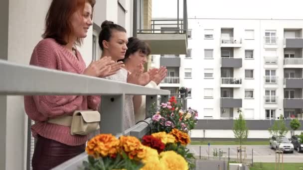 Tři ženy stojí na balkóně činžovního domu a radostně tleskají. Lidé jsou z něčeho šťastní.. — Stock video