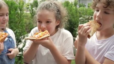 Üç okul çocuğu okulda tatil sırasında pizzanın tadını çıkarıyor..