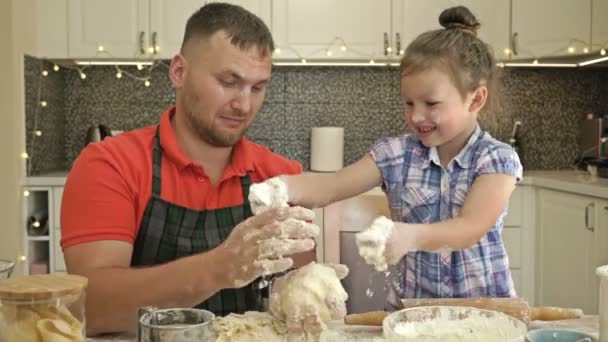 Papá y su hija, de 5 a 6 años, están amasando masa en la cocina. Parece un juego.. — Vídeos de Stock