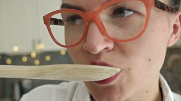 Jonge vrouw proeft het gerecht dat ze bereid heeft. Close-up. — Stockvideo