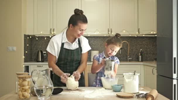 La hijita ayuda a su madre a cocinar un poco de masa. Tiempo familiar divertido y gratificante. — Vídeo de stock