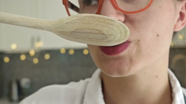 La joven prueba el plato que ha preparado. Primer plano. — Vídeo de stock