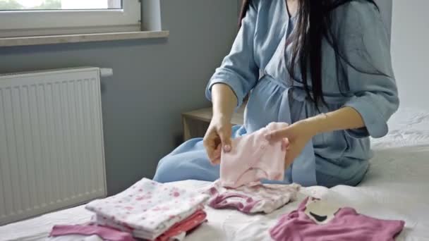 Belle femme enceinte regarde les choses pour un nouveau-né. Attentes d'un enfant, maternité. — Video