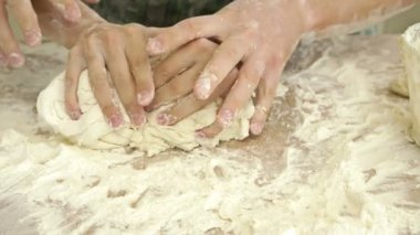 Erkek ve kadın elleri hamuru birlikte yoğurur. Yakın plan. Karşılıklı ilişki.