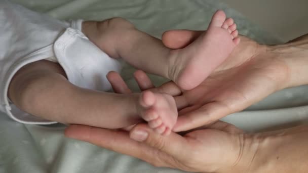 Mãe segura as pernas de seu bebê recém-nascido em suas mãos. Fechar.. — Vídeo de Stock