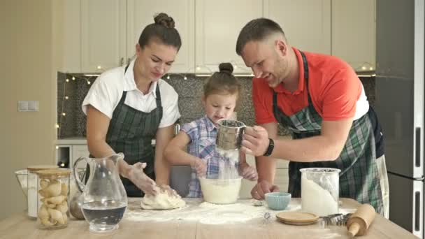 Wesoła para małżeńska z małą córeczką, ugotować razem trochę ciasta, cieszyć się aktywnościami rodzinnymi. — Wideo stockowe