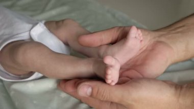 Anne yeni doğmuş bebeğinin bacaklarını elinde tutuyor. Yakın çekim..