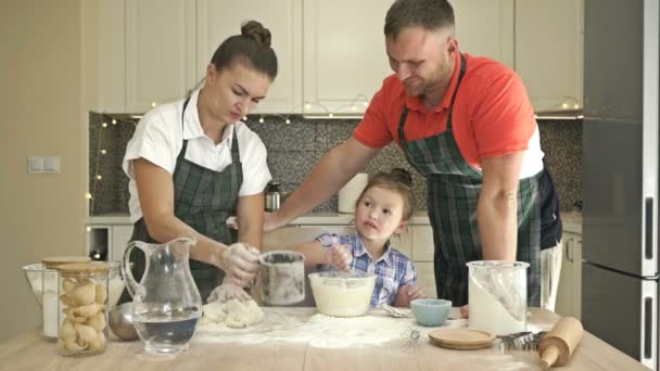 Veselá trojčlenná rodina připravuje něco na svátky v kuchyni. Všichni jsou ve skvělé náladě. — Stock video