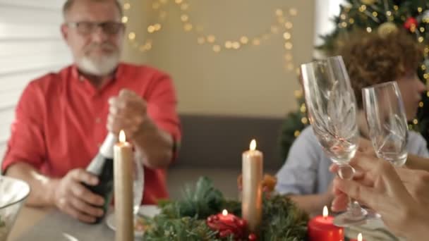 Uomo anziano, membro anziano della famiglia, aprendo una bottiglia di champagne e versando dello spumante nei bicchieri. — Video Stock