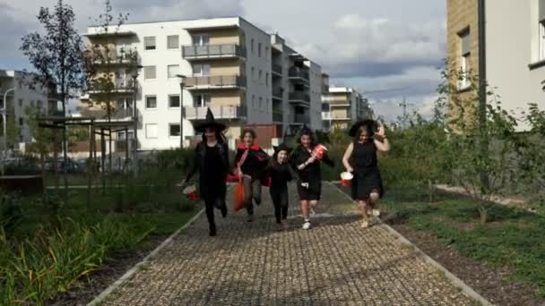 Un gruppo di bambini in costume nero con un trucco spaventoso in faccia sta correndo lungo la strada. Halloween è una festa per bambini preferita. Si stanno divertendo tutti.. — Video Stock