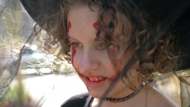 Portrait of a teenage girl dressed as a witch with scary makeup on her face. Halloween. — Stock Video