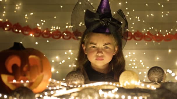 Pequena bruxa. Contra o pano de fundo dos atributos místicos do Halloween. As crianças adoram Halloween. — Vídeo de Stock