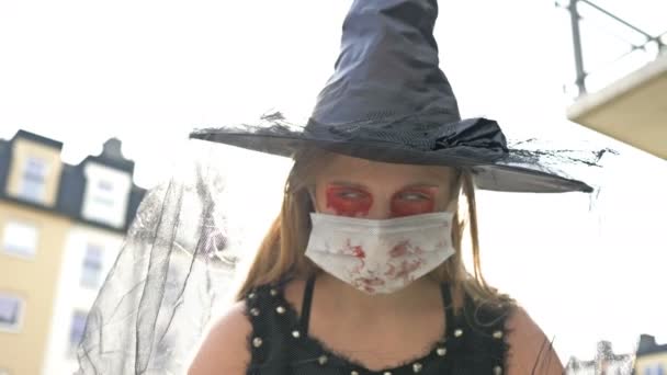 Ritratto di un'adolescente vestita da strega e con una maschera protettiva sul viso. Halloween durante la pandemia di coronavirus. — Video Stock
