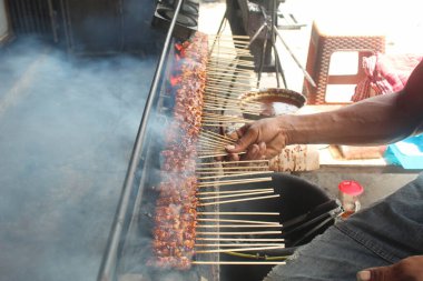 Eller ızgarada tipik Endonezya satayını pişiriyor.