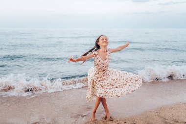 Kız sahilde iyi eğlenceler. Deniz kenarında bir elbise içinde dönüyor. Retro tarzı