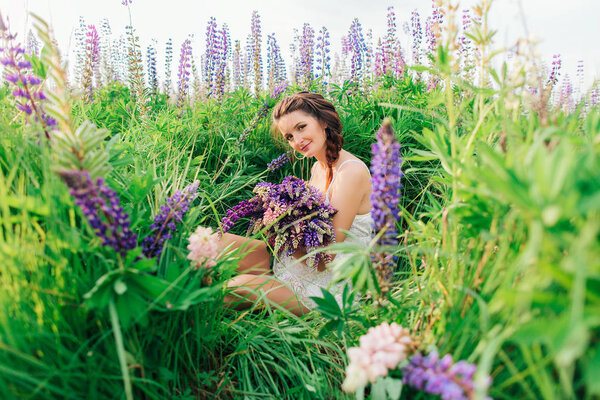 Beautiful girl with bouquet of lupine flowers in hands