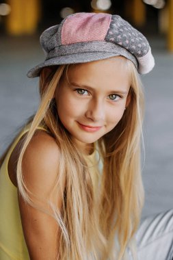 Şapkalı uzun sarı saçlı güzel bir kızın portresi. Sokak fotoğraf çekimi