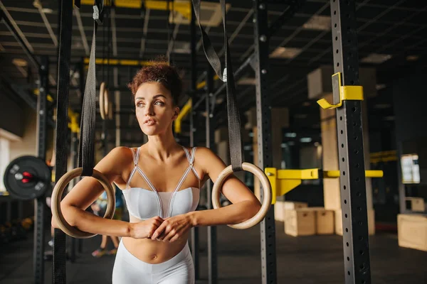 Sport Record. Fitness sports girl wearing in white top and leggings exercising on gymnastic rings in gym. Sport and health. Fitness life.