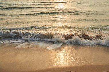 Küçük dalgalar. Deniz sahilinde portakal rengi gün batımı.