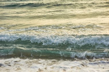 Küçük dalgalar. Deniz sahilinde portakal rengi gün batımı.