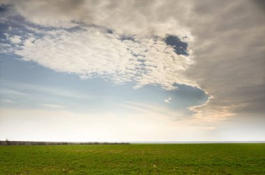 Gün batımı bulutlu gökyüzü ve yeşil çayırlar.