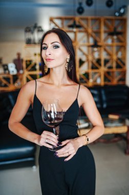 Gevşeme zamanı ve alkol teması. Güzel mutlu bayan bir bardak kırmızı şarap içiyor..