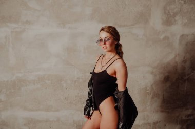 Rock konsepti. Siyah takım elbiseli ve deri ceketli çekici sarışın kadın portresi. Pembe güneş gözlükleri. 