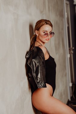 Rock konsepti. Siyah takım elbiseli ve deri ceketli çekici sarışın kadın portresi. Pembe güneş gözlükleri. 