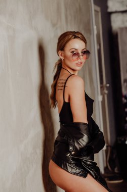 Rock konsepti. Siyah takım elbiseli ve deri ceketli çekici sarışın kadın portresi. Pembe güneş gözlükleri. 