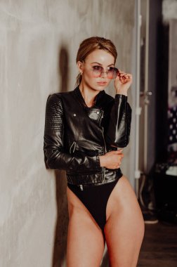 Rock konsepti. Siyah takım elbiseli ve deri ceketli çekici sarışın kadın portresi. Pembe güneş gözlükleri. 