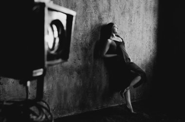 Beyaz tenli esmer kadının portresi. Siyah elbiseli ve tavan arasında poz veriyor.. 