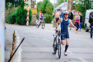 KHARKIV, UKRAINE - 2 Ağustos 2020 Demir Adam yarışması sırasında triatoncu bisikletli triatloncu bisikleti. Üç takım elbiseli ve kasklı bir bisiklet sporcusu. Halka açık etkinliklere izin var. CV salgını sırasında Avrupa sporu.