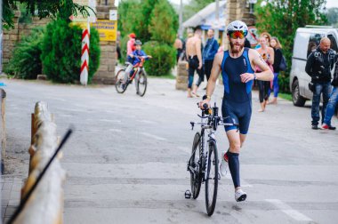 KHARKIV, UKRAINE - 2 Ağustos 2020 Demir Adam yarışması sırasında triatoncu bisikletli triatloncu bisikleti. Üç takım elbiseli ve kasklı bir bisiklet sporcusu. Halka açık etkinliklere izin var. CV salgını sırasında Avrupa sporu.