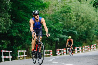 KHARKIV, UKRAINE - 2 Ağustos 2020 Demir Adam yarışması sırasında triatoncu bisikletli triatloncu bisikleti. Üç takım elbiseli ve kasklı bir bisiklet sporcusu. Halka açık etkinliklere izin var. CV salgını sırasında Avrupa sporu.