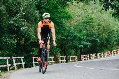 KHARKIV, UKRAINE - 2 Ağustos 2020 Demir Adam yarışması sırasında triatoncu bisikletli triatloncu bisikleti. Üç takım elbiseli ve kasklı bir bisiklet sporcusu. Halka açık etkinliklere izin var. CV salgını sırasında Avrupa sporu.