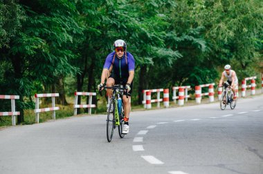 KHARKIV, UKRAINE - 2 Ağustos 2020 Demir Adam yarışması sırasında triatoncu bisikletli triatloncu bisikleti. Üç takım elbiseli ve kasklı bir bisiklet sporcusu. Halka açık etkinliklere izin var. CV salgını sırasında Avrupa sporu.