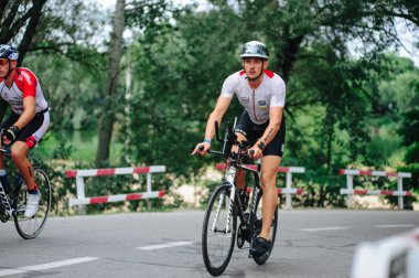 KHARKIV, UKRAINE - 2 Ağustos 2020 Demir Adam yarışması sırasında triatoncu bisikletli triatloncu bisikleti. Üç takım elbiseli ve kasklı bir bisiklet sporcusu. Halka açık etkinliklere izin var. CV salgını sırasında Avrupa sporu.