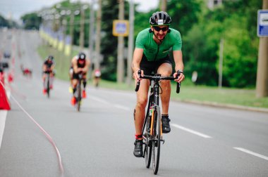 KHARKIV, UKRAINE - 2 Ağustos 2020 Demir Adam yarışması sırasında triatoncu bisikletli triatloncu bisikleti. Üç takım elbiseli ve kasklı bir bisiklet sporcusu. Halka açık etkinliklere izin var. CV salgını sırasında Avrupa sporu.