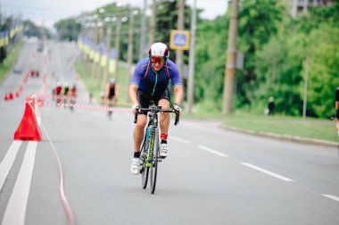 KHARKIV, UKRAINE - 2 Ağustos 2020 Demir Adam yarışması sırasında triatoncu bisikletli triatloncu bisikleti. Üç takım elbiseli ve kasklı bir bisiklet sporcusu. Halka açık etkinliklere izin var. CV salgını sırasında Avrupa sporu.