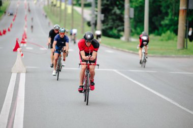 KHARKIV, UKRAINE - 2 Ağustos 2020 Demir Adam yarışması sırasında triatoncu bisikletli triatloncu bisikleti. Üç takım elbiseli ve kasklı bir bisiklet sporcusu. Halka açık etkinliklere izin var. CV salgını sırasında Avrupa sporu.