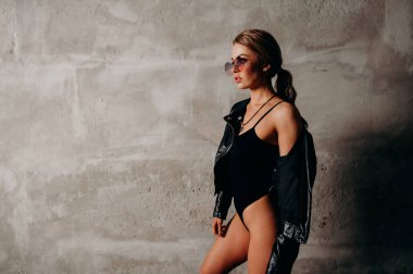 Siyah ceketli ve siyah elbiseli bir kadın. Pembe güneş gözlüklü rock yıldızı kız..