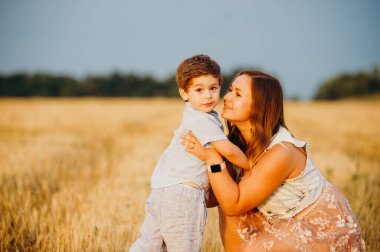 Yazın gün batımında annesi tarlada olan sevimli, neşeli bir çocuk. Aile kavramı 