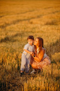 Yazın gün batımında annesi tarlada olan sevimli, neşeli bir çocuk. Aile kavramı 