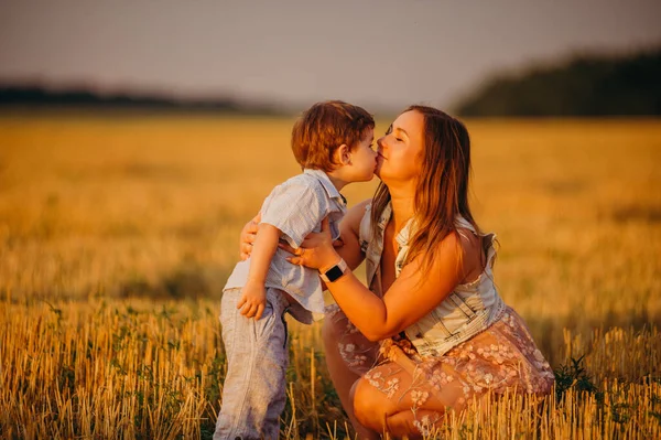 夏の日の日没時にフィールドに母親とかわいい陽気な子供の息子 家族の概念 — ストック写真
