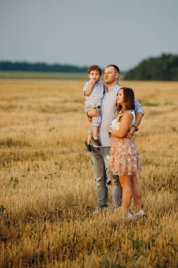Mutlu aile kavramı. Anne ve babanın oğlu. Güneşin altında mutlu bir aile var. Anne, baba ve oğul gün batımında mutlu yürüyüşler, ebeveynler bebeği tutuyor.. 