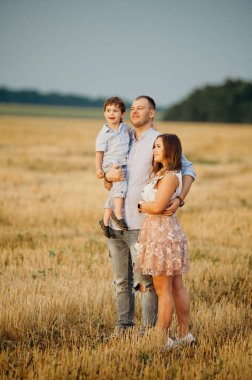 Mutlu aile kavramı. Anne ve babanın oğlu. Güneşin altında mutlu bir aile var. Anne, baba ve oğul gün batımında mutlu yürüyüşler, ebeveynler bebeği tutuyor.. 