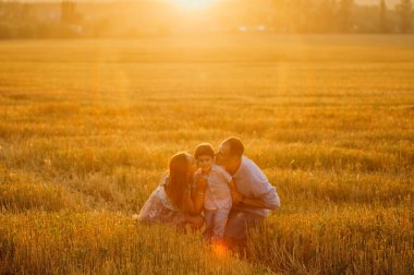 Mutlu aile kavramı. Anne ve babanın oğlu. Güneşin altında mutlu bir aile var. Anne, baba ve oğul gün batımında mutlu yürüyüşler, ebeveynler bebeği tutuyor.. 